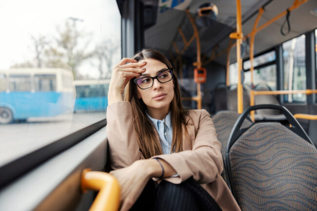 Worried young woman sitting in public bus and getting nervous during ride.
