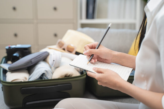 person checking list of stuff to prepare suitcase before travel