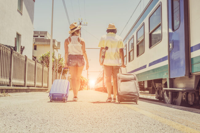Loving tourists holding suitcases at the train station